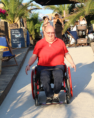 Richard J. Schäfer fährt im Rollstuhl einen Strandweg entlang.